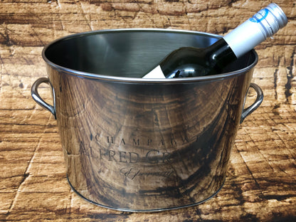 “Luxe Alfred Gratien champagne‑emmer van roestvrij staal met warme houtlook, gevuld met een gekoelde champagnefles. De emmer staat op een houten oppervlak en toont duidelijk het Alfred Gratien Épernay‑logo, wat zorgt voor een elegante en authentieke presentatie van wijn- en champagneaccessoires.”