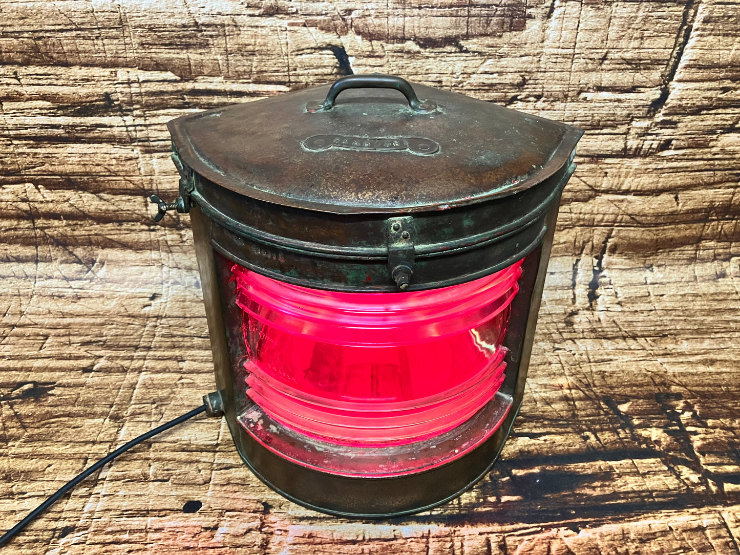 Oude koperen scheepslamp met verlichting en glas.