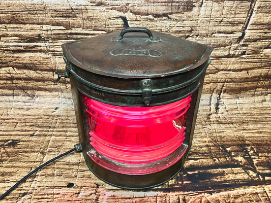 Oude koperen scheepslamp met verlichting en glas.