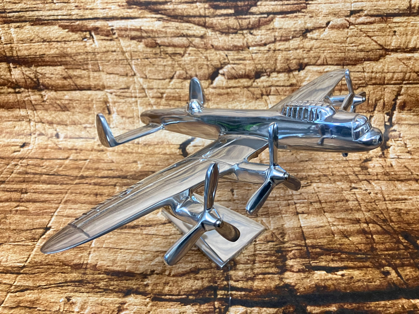 Gepolijst metalen model van een viermotorig propellervliegtuig met cockpitdetails en twee propellers per vleugel, gemonteerd op een standaard.