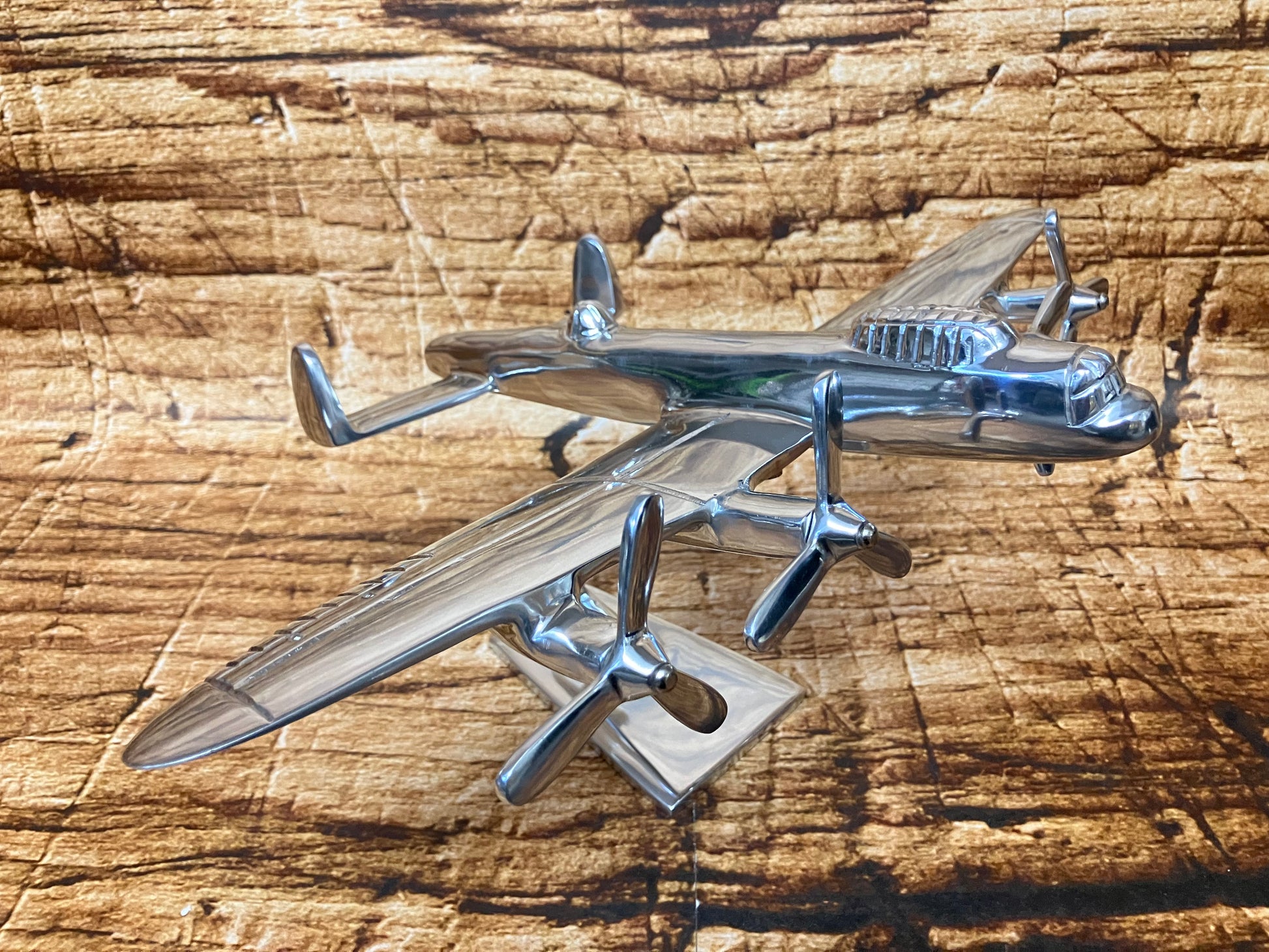 Gepolijst metalen model van een viermotorig propellervliegtuig met cockpitdetails en twee propellers per vleugel, gemonteerd op een standaard.