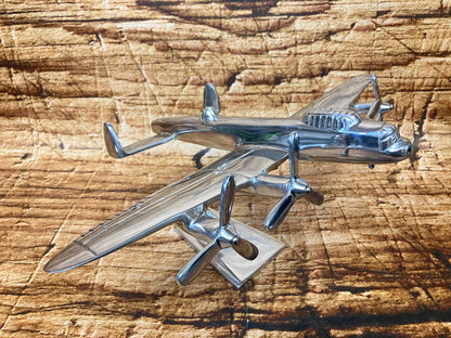 Gepolijst metalen model van een viermotorig propellervliegtuig met cockpitdetails en twee propellers per vleugel, gemonteerd op een standaard.