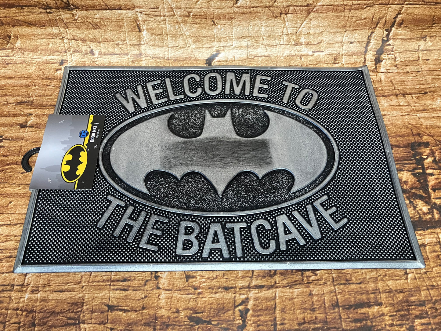 Zwart‑grijze Batman‑deurmat met het vleermuislogo en de tekst “Welcome to the Batcave".