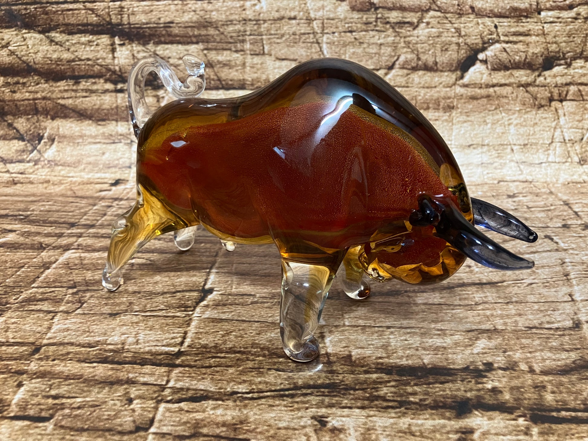 Glazen stier in amber en helder glas met donkere hoorns, krachtig gevormd.