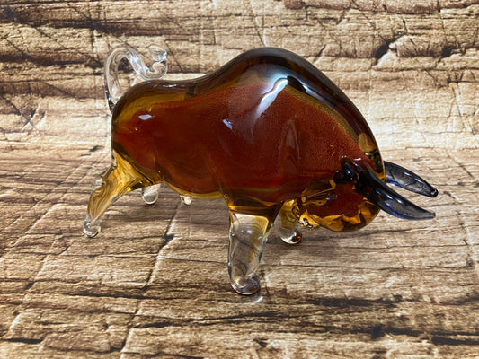 Glazen stier in amber en helder glas met donkere hoorns, krachtig gevormd.