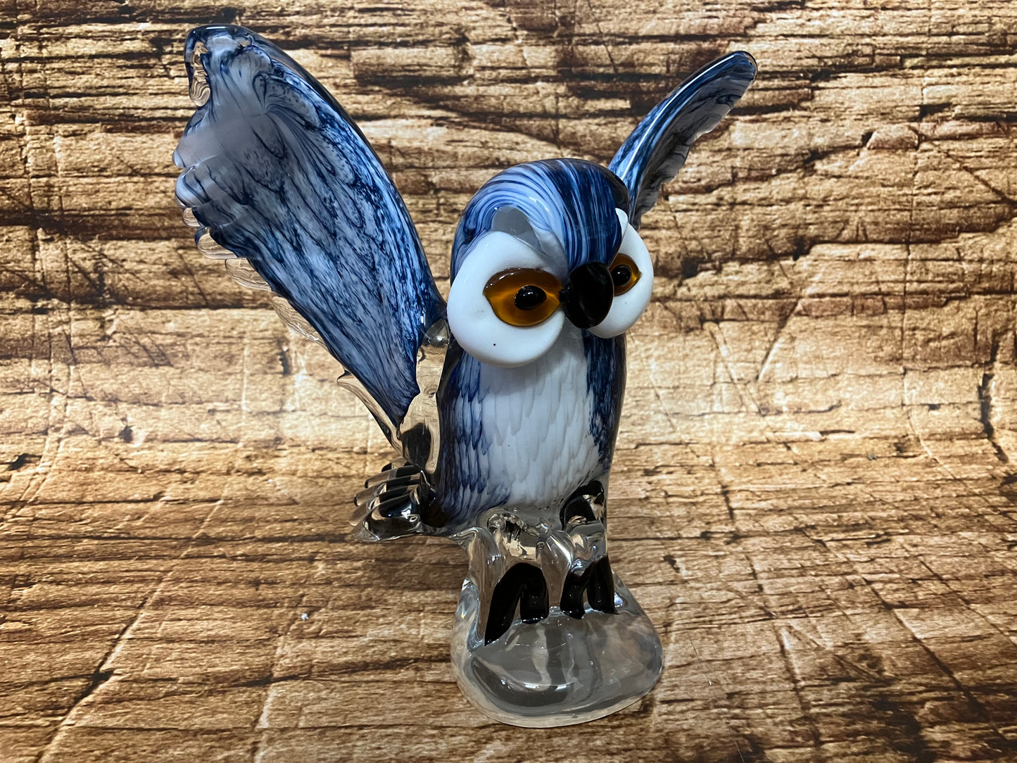 Glazen uil met gespreide vleugels in blauw, wit en zwart, met oranje ogen en transparante voet.