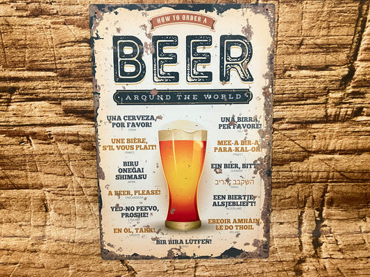 Decoratief bord met de tekst “How to Order a Beer Around the World” en een illustratie van een bierglas, met vertalingen van “Een biertje, alsjeblieft” in diverse talen en landen, op een verweerde achtergrond gemonteerd op hout.
