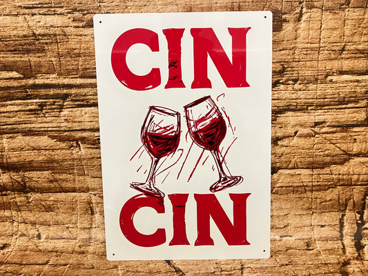 Decoratief bord met de tekst “CIN CIN” in rode letters boven en onder een illustratie van twee proostende wijnglazen, op een rustieke houten achtergrond met feestelijke uitstraling.