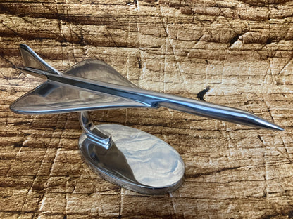 Gepolijst metalen model van een Concorde-achtig supersonisch vliegtuig met scherpe neus en delta-vleugels, gemonteerd op een gebogen standaard met ovale voet.