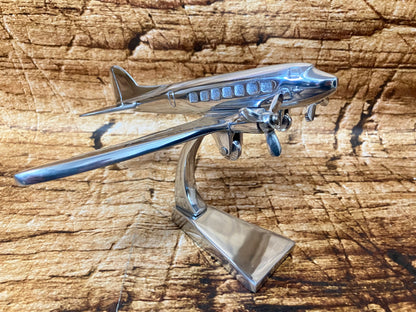 Glanzend metalen vliegtuigmodel met dubbele propellers op een gebogen standaard, geschikt als luxe decoratie voor mancave, kantoor of vintage interieur.