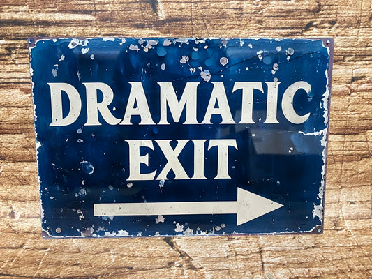  Vintage metalen bord met verweerde blauwe achtergrond en witte tekst “DRAMATIC EXIT” met een pijl naar rechts, gemonteerd op een bakstenen muur voor een theatrale en humoristische uitstraling.