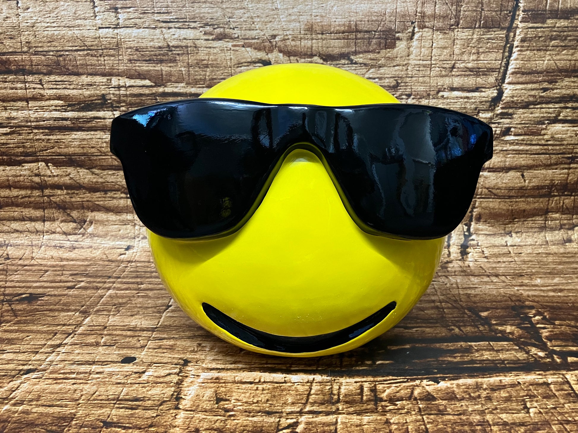 Groot geel polyester beeld van een Emoji met zwarte zonnebril.