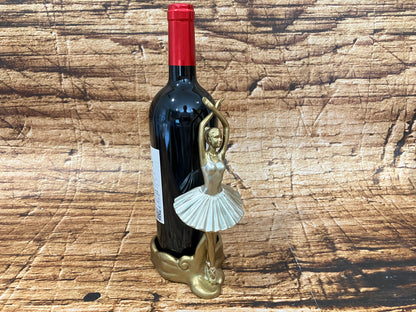 Alt‑tekst:
Een gouden ballerina wijnhouder in elegante pointe‑pose ondersteunt een donkere wijnfles met rode capsule