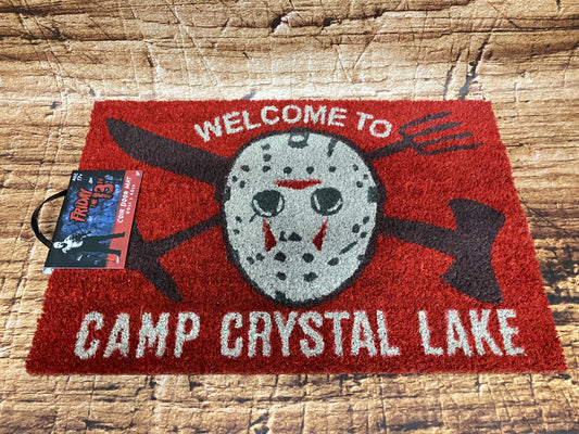 Rode Friday the 13th deurmat met Jason Voorhees‑masker, gekruiste wapens en de tekst “Welcome to Camp Crystal Lake”.
