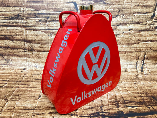 "Rode vintage Volkswagen metalen brandstof- of oliekannister met grijs VW‑logo, driehoekige vorm, messing dop en dubbele handgrepen, gebruikt als oldtimer- en garage‑decoratie."