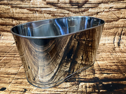 Ovale metalen wijnkoeler met spiegelende afwerking, geplaatst op een houten ondergrond, geschikt voor meerdere flessen wijn of champagne met ijs.