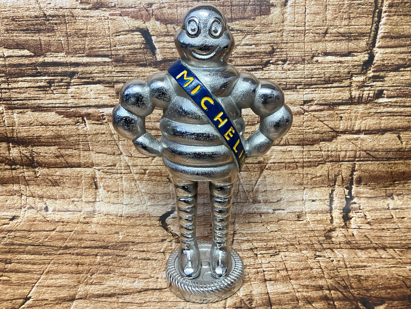 Metalen Michelin Man (Bibendum) beeldje met blauwe Michelin‑sjerp, geschikt als automotive decoratie of verzamelobject.