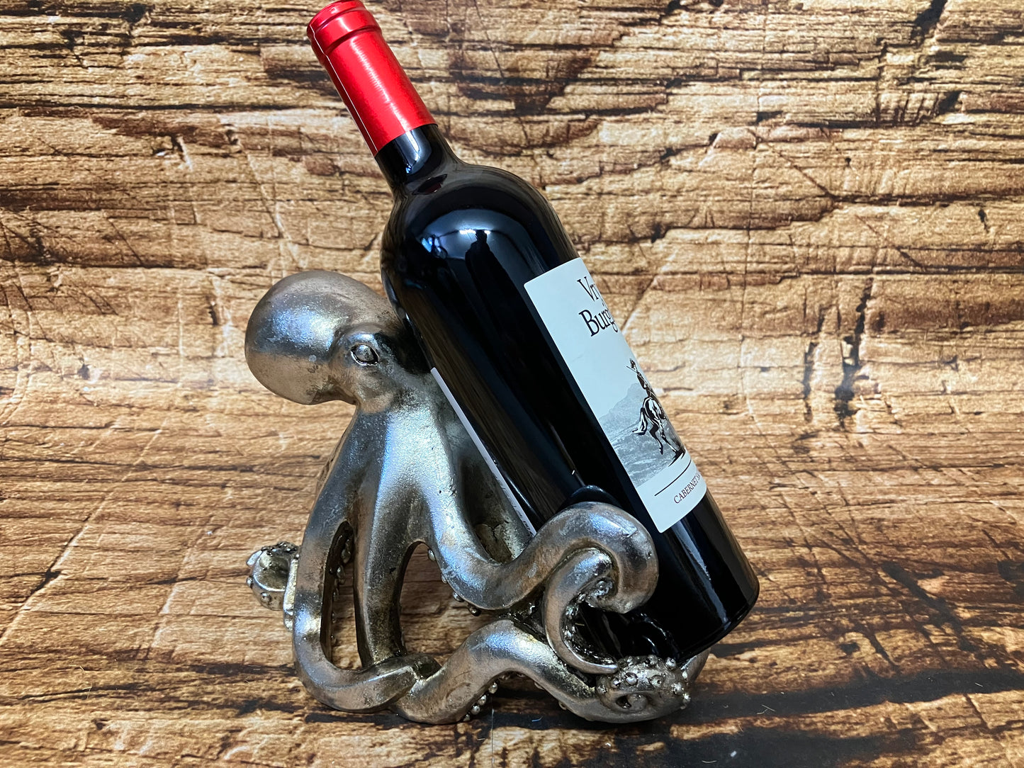 Zilverkleurige octopus‑wijnfleshouder die een wijnfles vasthoudt met zijn tentakels.