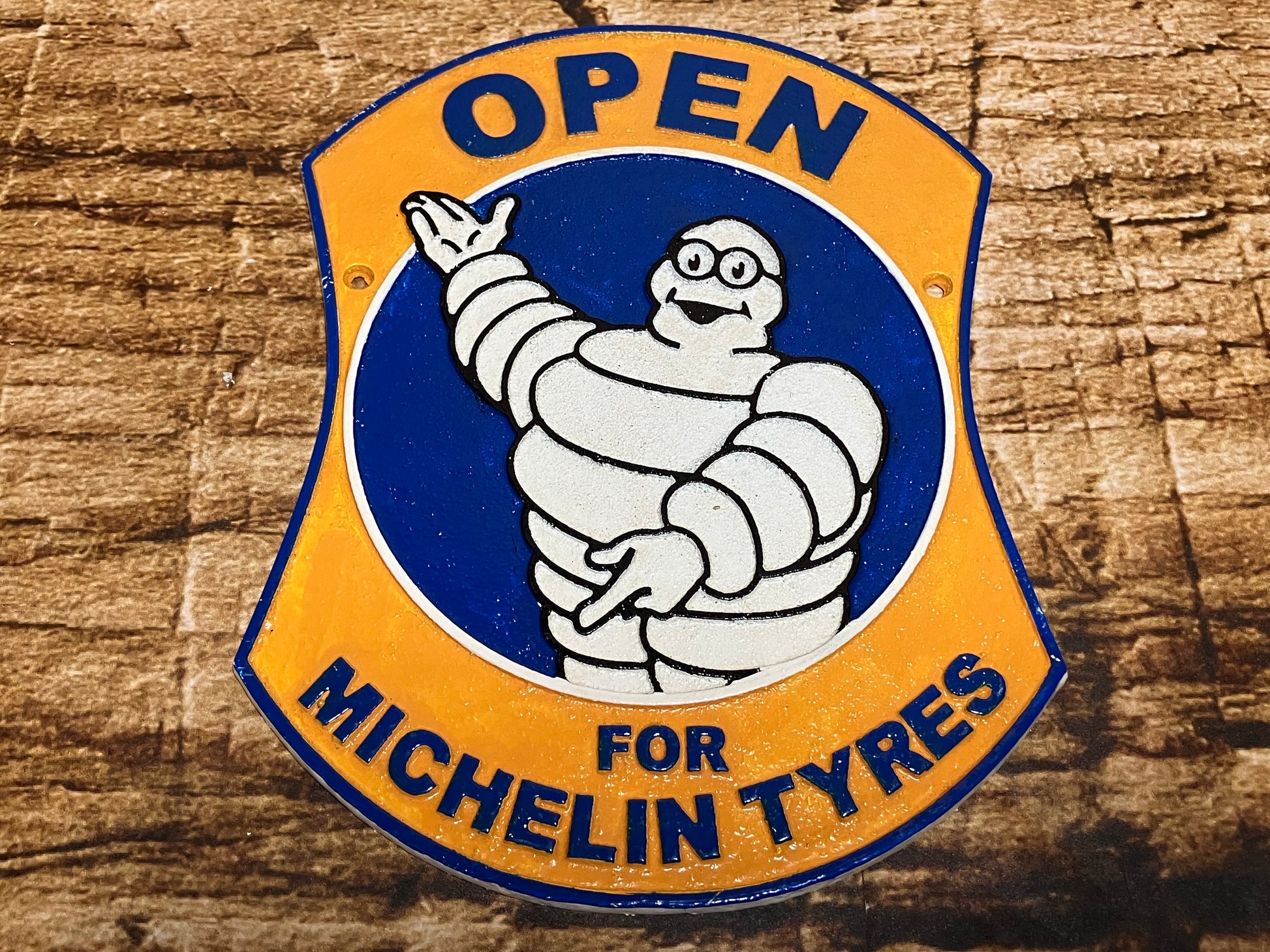 Vintage metalen Michelin‑bord met de Michelin Man (Bibendum) in blauw‑gele stijl en de tekst “Open for Michelin Tyres”, geschikt als retro wanddecoratie voor garage of mancave.