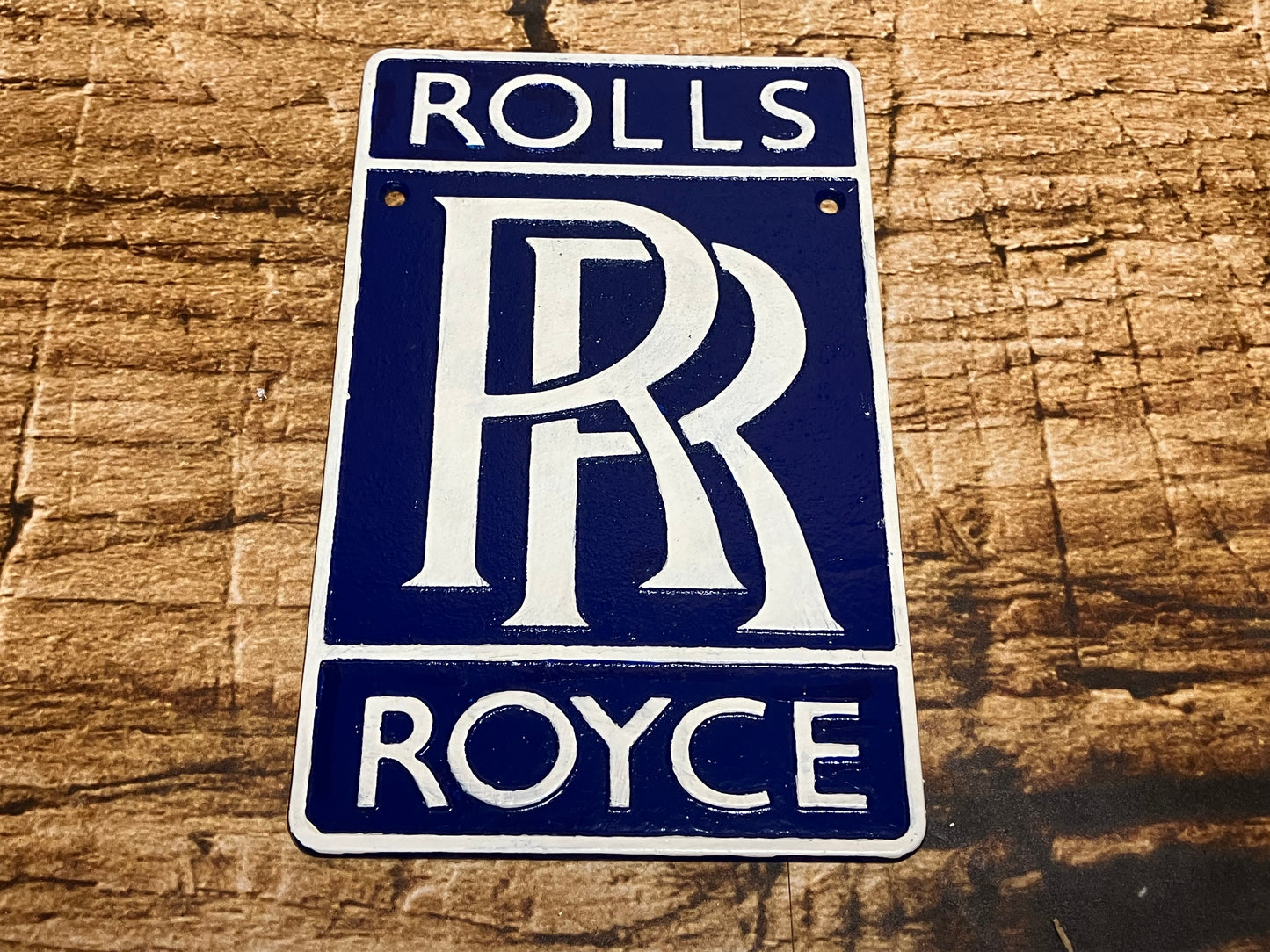Gietijzeren Rolls‑Royce wandplaat in blauw met wit reliëf en het iconische RR‑logo.