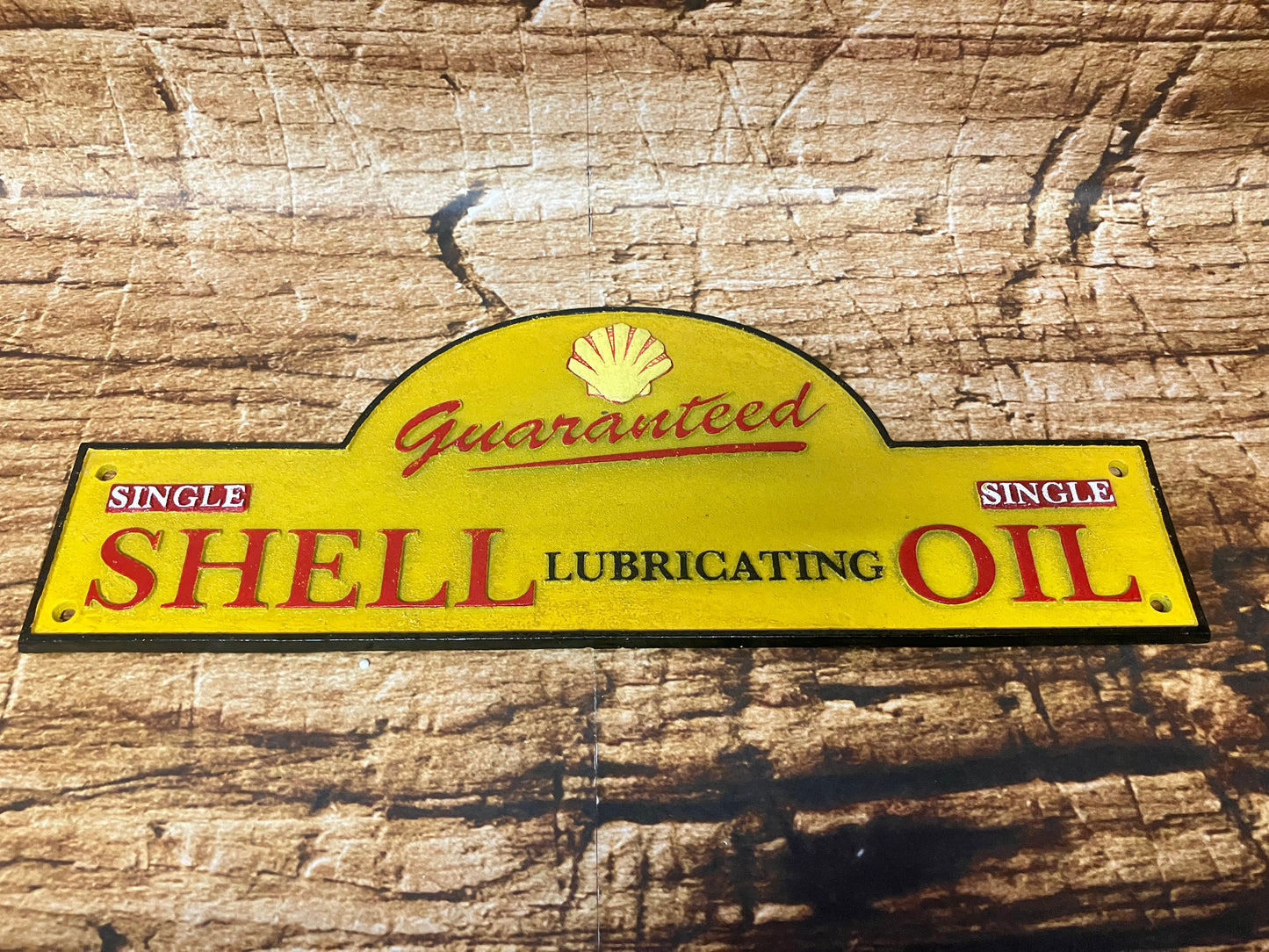 Vintage metalen Shell reclamebord met geel achtergrond, rood logo en de tekst “Guaranteed Single Shell Lubricating Oil”, geschikt als industriële decoratie voor mancave of garage.