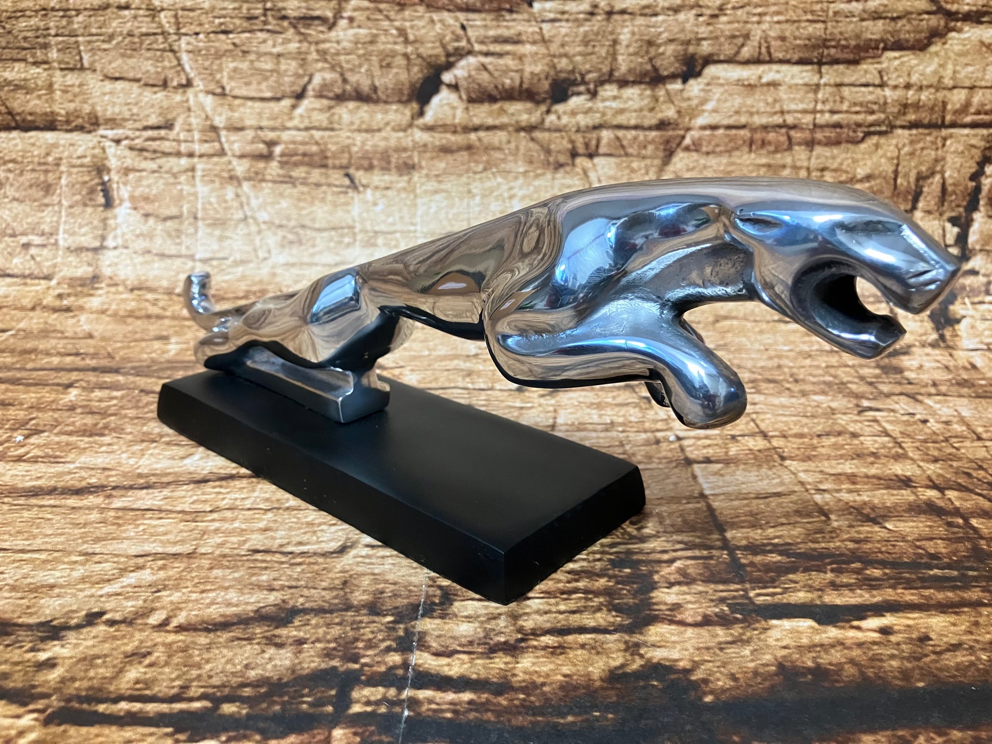 “Luxe gepolijst metalen jaguar beeldje op zwarte basis, modern decoratieobject dat kracht, snelheid en elegantie uitstraalt, ideaal voor interieur, kantoor of showroom.”