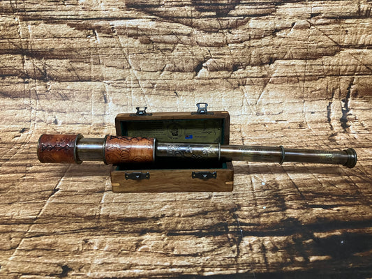 "Vintage messing telescoop met houten details in open houten box met decoratieve gravures, gebruikt als maritiem en decoratief verzamelobject."