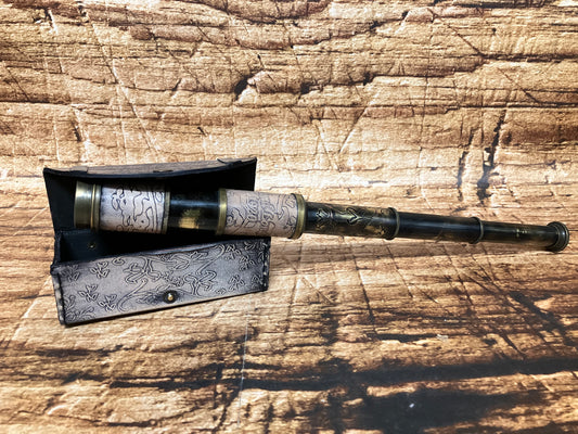“Antieke messing telescoop met lederen details en sierlijke gravures, deels uitgeschoven en rustend op een bijpassende decoratieve kist, geplaatst op een verweerd, vintage oppervlak dat de klassieke en historische uitstraling versterkt.”