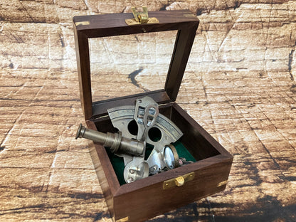 "Vintage nautische sextant in houten box met glasplaat, metalen onderdelen en groene viltvoering, gebruikt als decoratief en verzamelobject."