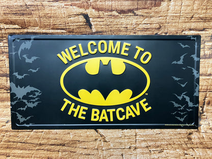 Metalen wandbord met de tekst “Welcome to the Batcave”, zwart met geel Batman‑logo en vliegende vleermuizen, geschikt voor mancave of industriële decoratie.