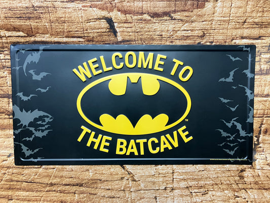 Metalen wandbord met de tekst “Welcome to the Batcave”, zwart met geel Batman‑logo en vliegende vleermuizen, geschikt voor mancave of industriële decoratie.