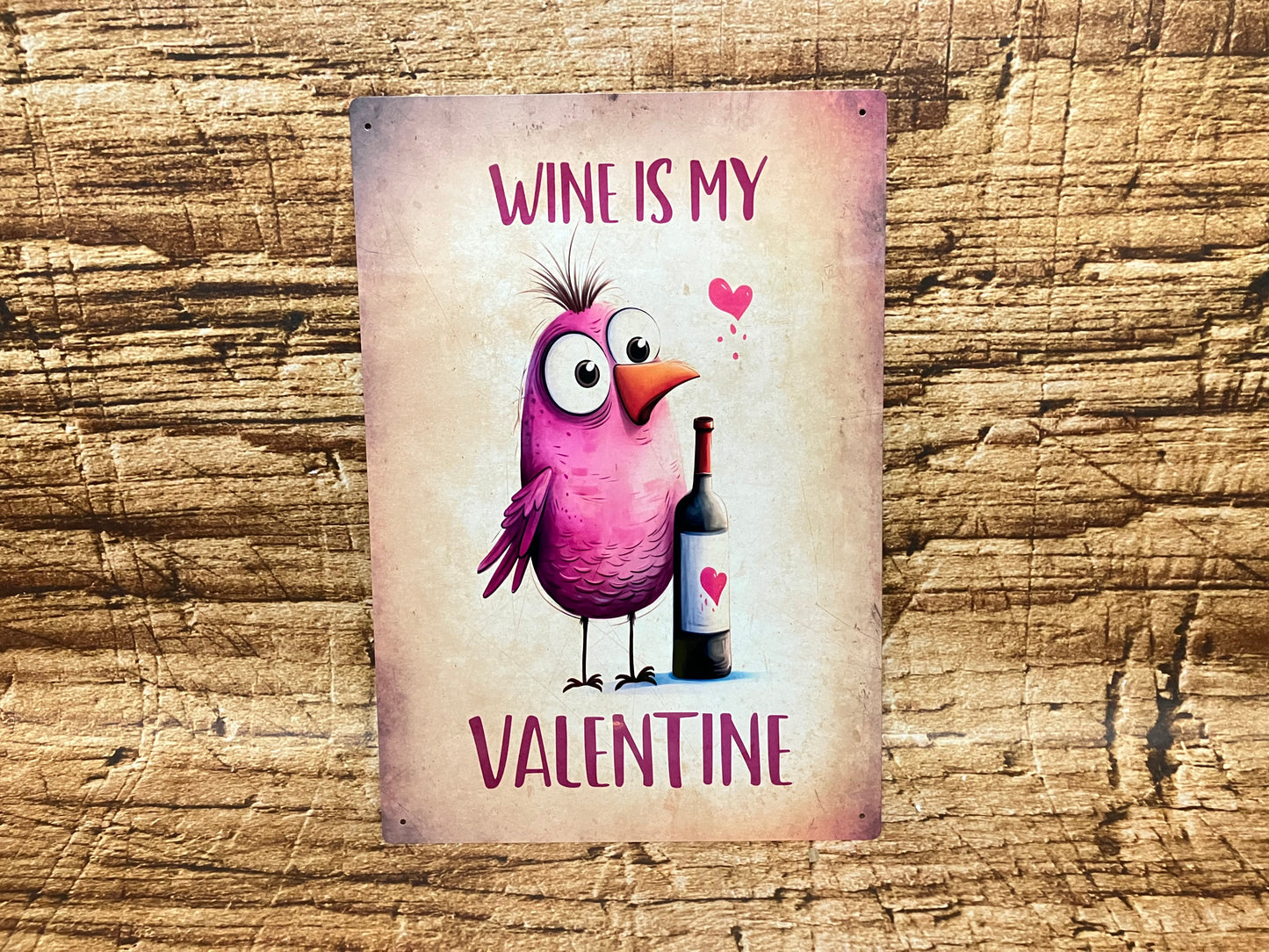 Humoristisch decoratief bord met een paarse cartoonvogel naast een wijnfles met hartlabel, omringd door roze hartjes en de tekst “WINE IS MY VALENTINE” op een rustieke achtergrond.