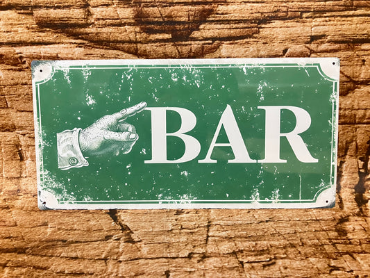  Vintage metalen bord met groene achtergrond en witte tekst “BAR” naast een wijzende hand naar links, met verweerde randen en gemonteerd op hout voor een nostalgische en functionele uitstraling.