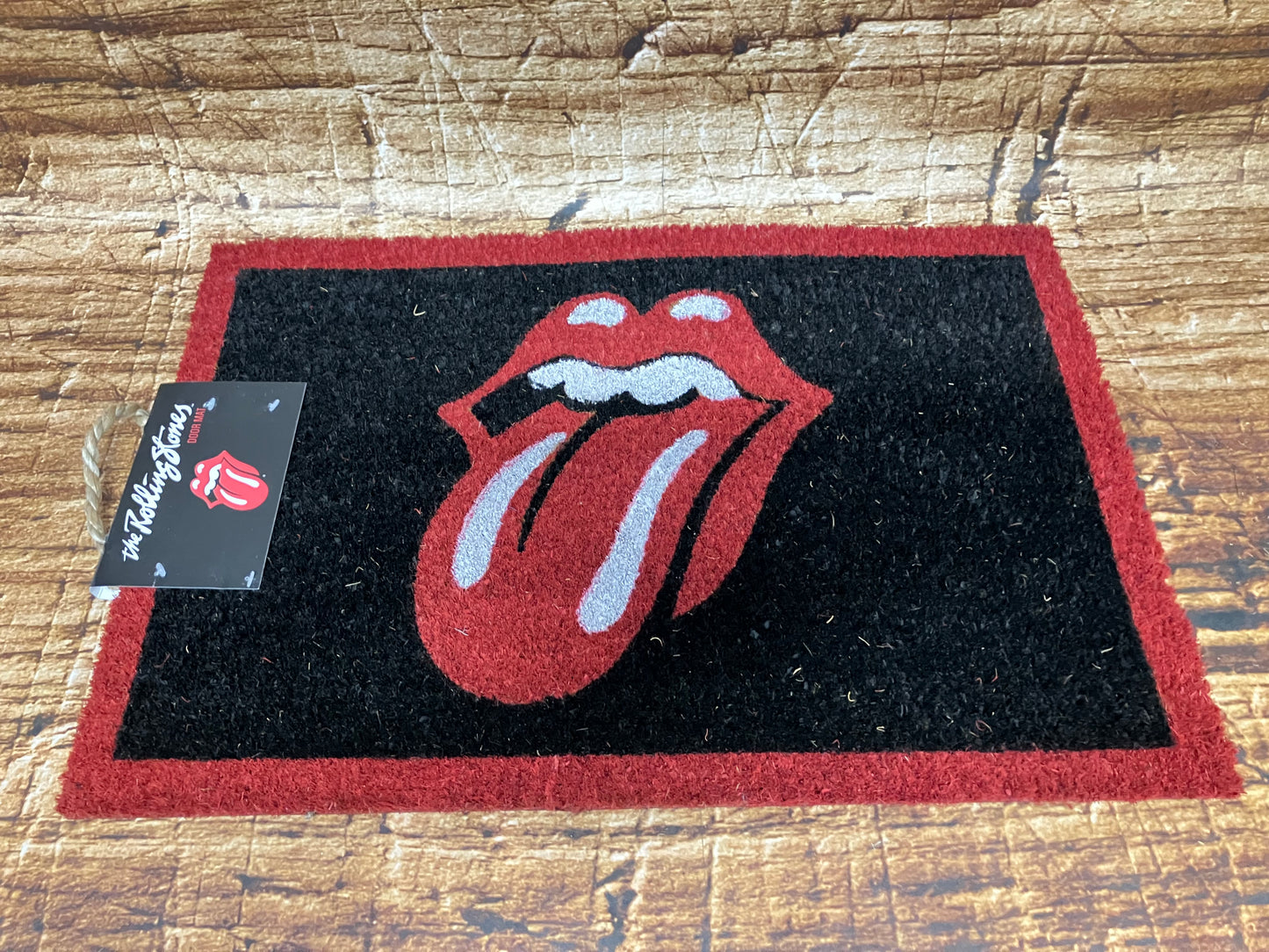 "Zwarte Rolling Stones deurmat met rood tong‑en‑lip logo en rode rand, geschikt voor rockfans en muziekdecoratie."